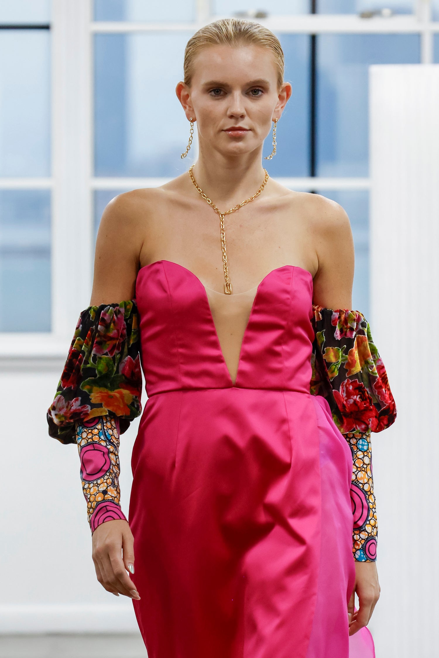 Robe bustier fluide rose et fuchsia avec un décolleté plongeant, manches bouffantes ornées d’un motif floral et wax coloré, et jupe asymétrique.